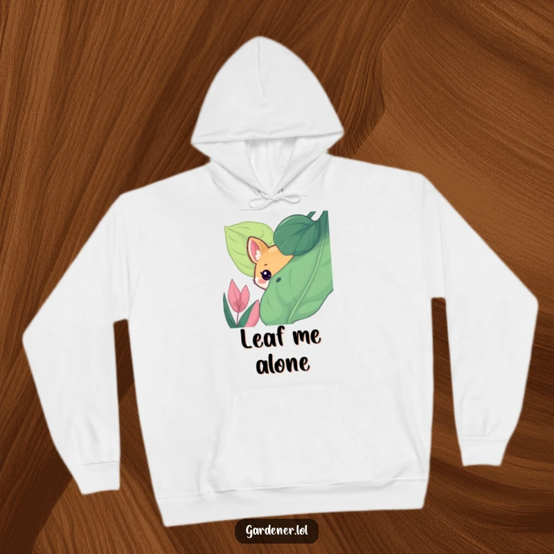 Funny hoodie depicting a cute animal character playfully peeking from behind a large, lush leaf, a scene of cozy, curious fun.